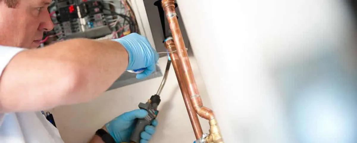 Water heater repair technician testing copper pipe connections and controls in Clearwater, FL